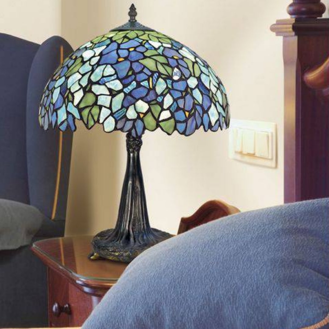 Lampe Tiffany à abat-jour en vitrail multicolore, sur une table de chevet dans une chambre. histoire de l'art du vitrail.