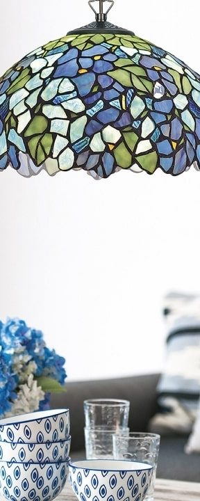 Abat-jour Tiffany mosaïque coloré suspendu au-dessus d'une table avec des bols décoratifs et des verres translucides.