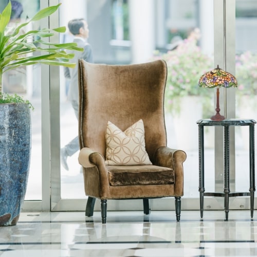 Chaise tendance et lampe Tiffany sur pied près d’une table, dans un intérieur lumineux.