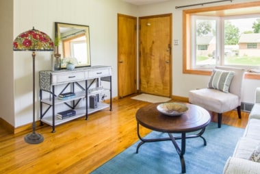 Intérieur d’un salon art déco avec mobilier en bois, tapis bleu et table basse circulaire.