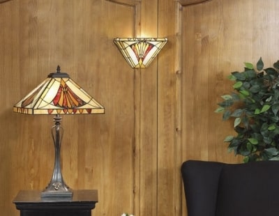 Lampe décorative en verre sur pied près d’un mur en bois et d’un canapé noir.