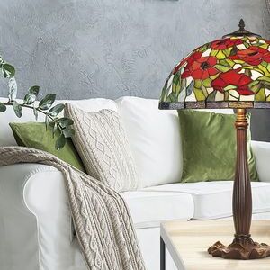 Une lampe Tiffany au style mosaïque colorée posée sur une table à côté d’un canapé blanc et de coussins verts.