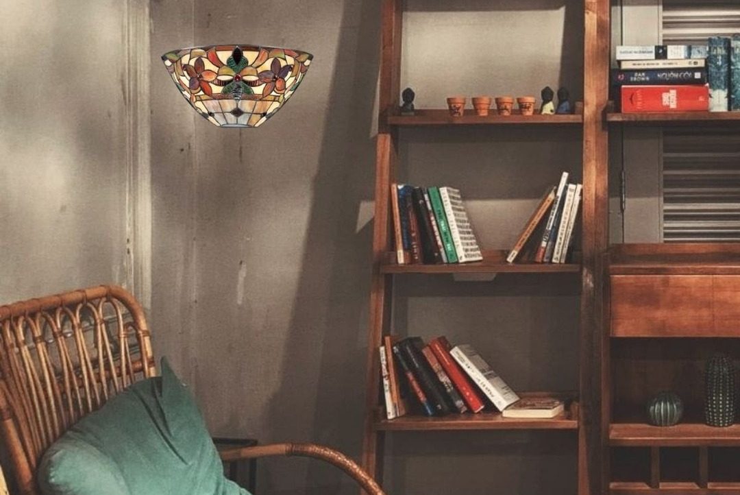 Une lampe Tiffany suspendue au-dessus d'une étagère en bois remplie de livres dans un salon au style vintage.
