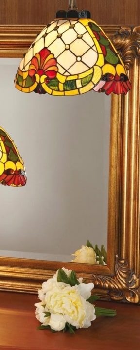 Suspension Tiffany colorée en verre multicolore pendue près d’un miroir doré.